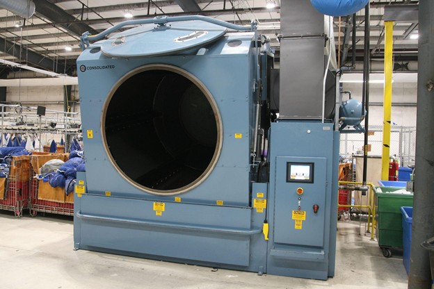 High-capacity industrial dryer running on a high-volume laundry plant floor